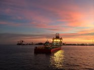 Navio de apoio à plataforma de petróleo iluminado que chega ao porto portuário ao entardecer — Fotografia de Stock