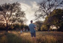 Отец и четверо детей гуляют по сельской местности в сумерках, Техас, Америка, США — стоковое фото