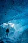Donna che cammina attraverso una grotta ghiacciata, Ghiacciaio Vatna, Islanda — Foto stock