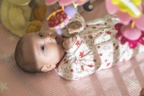 Glückliches kleines Mädchen liegt mit Spielzeug im Kinderbett — Stockfoto