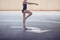 Ballet dancer girl dancing outdoors standing on white arrow sign — Stock Photo