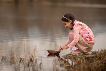 Девушка играет с бумажной лодкой в реке — стоковое фото
