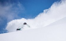 Hombre polvo esquí en la pendiente con el cielo azul en el fondo - foto de stock