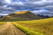 Iceland, Westfjords, Road and volcano on cloudy day — Stock Photo