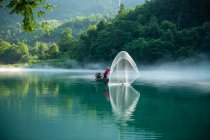 Mann im Boot wirft Fischernetz, chenzhou, hunan, China — Stockfoto
