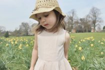 Дівчина в солом'яному капелюсі, що стоїть у полі — стокове фото