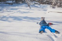 Дівчина лежить спереду в снігу в зимовому лісі — стокове фото