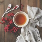 Bagas vermelhas e chá sobre mesa de madeira — Fotografia de Stock