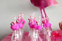 Pink flamingo straws in glass bottles in a row — Stock Photo