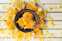 Желтые розы в миске на деревянном столе — стоковое фото