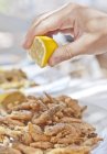 Imagen recortada de mano masculina exprimiendo limón en langoustines salteados - foto de stock