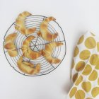 Croissants on metal cooling rack with tea towel — Stock Photo