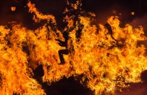 Silueta del hombre corriendo a través del fuego por la noche - foto de stock