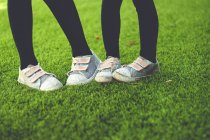 Baixa seção de duas meninas usando tênis na grama verde — Fotografia de Stock