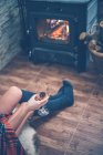 Обрізане зображення привабливої жінки з красивою шкірою в светрі і шкарпетках, що сидять біля каміна вдома і тримають келих вина — стокове фото