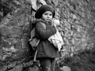 Menina segurando ursinho na frente da parede de tijolo — Fotografia de Stock