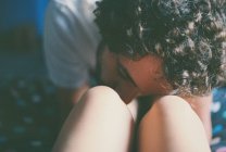 Молодой кудрявый мужчина целует колени подружки, крупным планом — стоковое фото