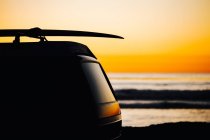 Silhueta de carro com prancha de surf no telhado contra belo pôr do sol em San Diego, Califórnia, América, EUA — Fotografia de Stock