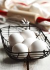 Fünf frische Eier in einem Korb auf weißem Holz — Stockfoto