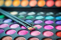 Primer plano de la paleta de sombras de ojos multicolores y maquillaje de pinceles - foto de stock