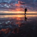 Silhouette eines Mannes, der bei Sonnenuntergang am Strand entlang läuft — Stockfoto