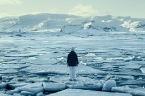 Donna in piedi su un lastrone di ghiaccio sul lago ghiacciato, Islanda — Foto stock