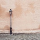 Вуличний ліхтар на брукованій вулиці рожевою стіною — стокове фото