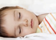 Primo piano della bambina addormentata a letto — Foto stock