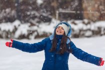 Дівчина з простягнутими руками грає в снігу — стокове фото