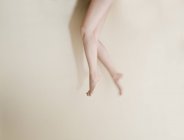 Низька секція молодих жіночих ніг на бежевому фоні — стокове фото