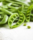 Fresh green whole and opened peas on wooden surface — Stock Photo