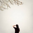 Rückansicht eines Mädchens, das einen blühenden Baum betrachtet — Stockfoto