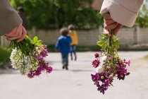Duas mulheres e dois meninos indo para andar e segurando flores — Fotografia de Stock