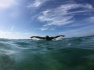 Mulher nadando no oceano com céu nublado no fundo — Fotografia de Stock