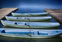 Barcos de remos en una fila amarrados en embarcadero - foto de stock