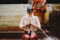 Cambodia, Buddhist monk water blessing young woman — Stock Photo
