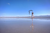 Woman holding scarf and jumping at salt lake, Qinghai, China — Stock Photo