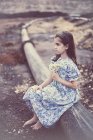 Chica sosteniendo un ramo de flores mientras se sienta en el tubo - foto de stock