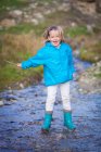 Glückliches blondes Mädchen spielt mit Stock im Fluss — Stockfoto