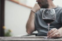 Крупним планом чоловік сидить з келихом червоного вина — стокове фото