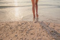 Обрезанное изображение женских ног, идущих по пляжу — стоковое фото