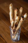Bread sticks in glass over wooden table — Stock Photo