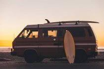 Surfbrett lehnt am Surfbus bei Sonnenuntergang, Kalifornien, Amerika, USA — Stockfoto