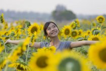 Lächelndes Teenagermädchen steht im Sonnenblumenfeld — Stockfoto