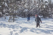 Vista posteriore di due ragazzi che corrono nella neve invernale — Foto stock
