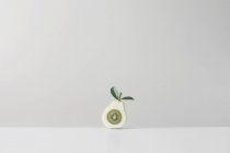 Kiwi fruit inside halved pear against grey wall — Stock Photo