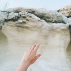 Обрезанное изображение рука тянется к скалам — стоковое фото