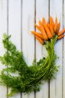 Bunch of carrots on wooden table, top view — Stock Photo