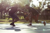 Двоє молодих чоловіків грають у баскетбол у парку на заході сонця — стокове фото
