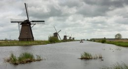 Molinos de viento tradicionales a lo largo de un río, Kinderdisk, Países Bajos - foto de stock